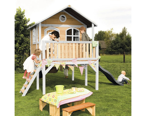 Spielhaus mit Rutsche, Leiter und Picknicktisch im Garten mit spielenden Kindern