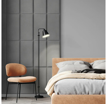 Schlafzimmer mit Bett, Stuhl und Stehlampe.
