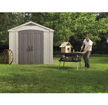 Gartenszene mit Gerätehaus und einer Person, die an einer Werkbank arbeitet