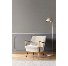 Interieuransicht mit Sessel und Stehlampe vor grauer Wand