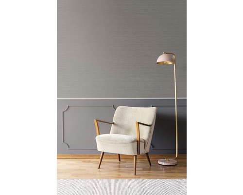 Interieuransicht mit Sessel und Stehlampe vor grauer Wand