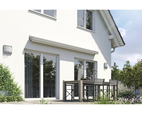 Hausfassade mit Markise über der Terrassentür und Gartentisch mit Stühlen