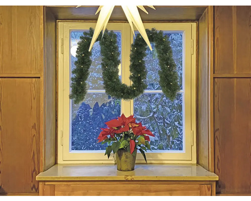 Dekoriertes Fenster mit Weihnachtsstern, Girlande und Weihnachtsstern-Blume