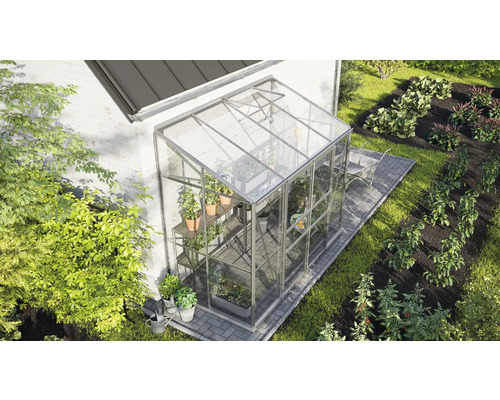 Gewächshaus aus Glas im Garten mit Pflanzen und Gemüsebeeten