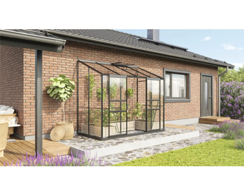 Gewächshaus mit Pflanzen auf einer Terrasse neben einem Wohnhaus.