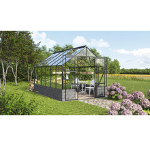 Gewächshaus mit Glas, Metallrahmen und Steinmauer im Garten