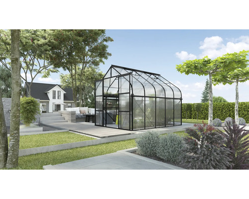 Gewächshaus im Garten mit Haus im Hintergrund.