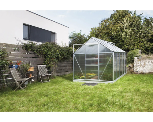 Gewächshaus im Garten mit Rasenfläche und Gartenmöbeln