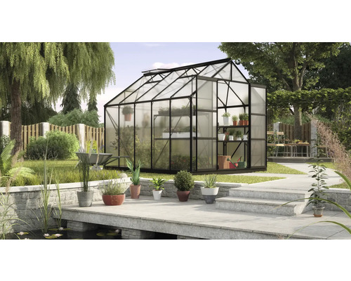 Gewächshaus mit Pflanzenregalen in einem Garten mit Teich