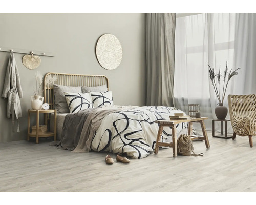 Helles Schlafzimmer mit Bett, Holzbeistelltisch und Rattansessel