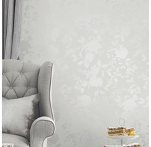 Szene mit Stuhl, Vorhang, Kuchen und floral gemusterter Tapete für ein helles, organisiertes Ambiente