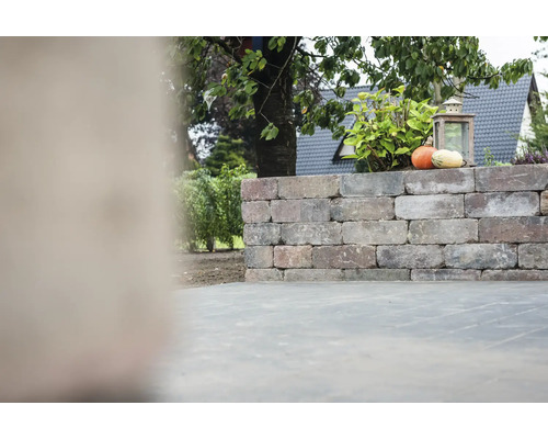 Mauer aus Ziegelsteinen mit Kürbissen und einer Laterne im Garten