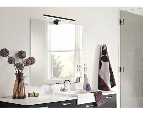 Modernes Badezimmer mit Waschbecken, Spiegel, Lampe und Dekorationen.