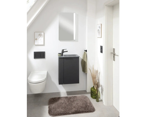 Modernes Badezimmer mit Toilette, Waschtisch, Spiegel und Badteppich.