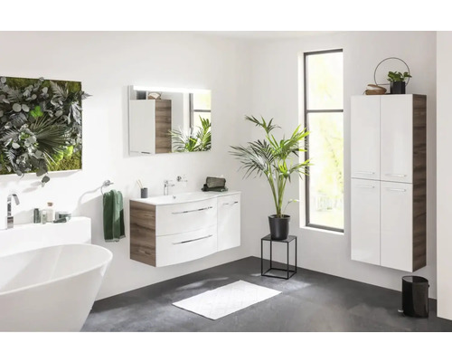 Badezimmer mit Waschtisch, Spiegel, Hochschrank, Badewanne und Dekorationen für eine helle und moderne Atmosphäre