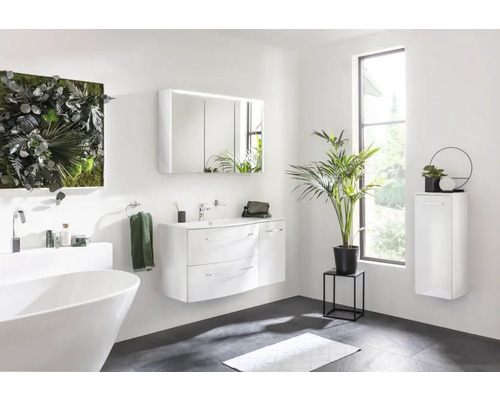 Badezimmer mit freistehender Badewanne, Waschtisch mit Spiegel, Hängeschrank und Pflanzendekoration für ein helles und modernes Ambiente.