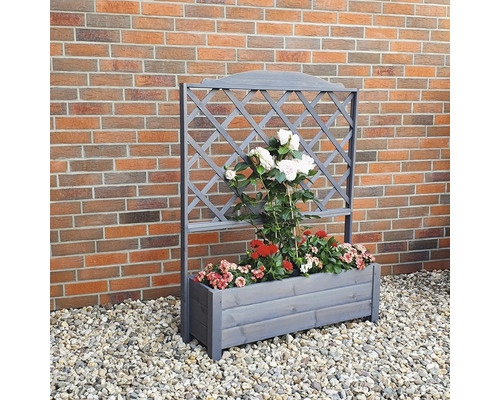 Holzpflanzkasten mit Rankgitter und Bepflanzung vor einer Ziegelwand