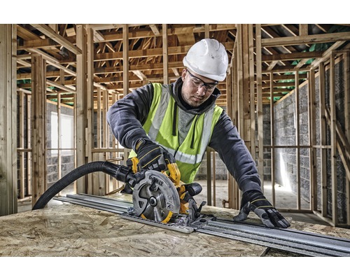 Ein Arbeiter benutzt eine Tauchsäge auf einer Holzplatte, umgeben von einem Holzrahmen