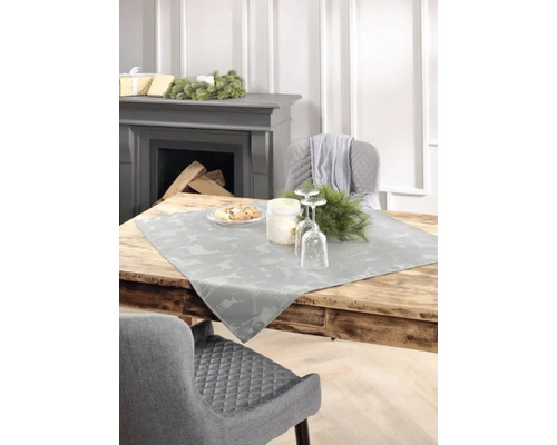 Dekorativer Esstisch mit Tischläufer, Gedeck und Kamin im Hintergrund.