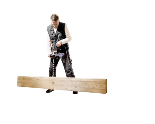 Ein Mann bohrt mit einer Bohrmaschine in ein Holzbrett.