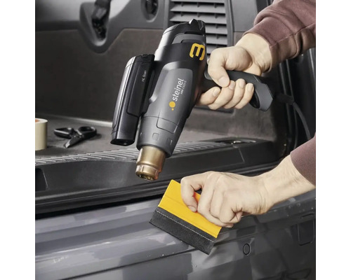 Heißluftpistole im Einsatz zum Anbringen von Folie mit einem Rakel.