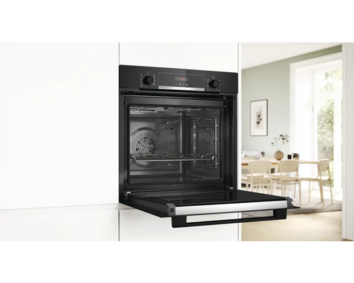 Einbauofen mit geöffneter Tür in einer hellen Küche.