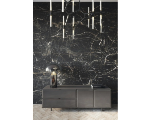 Dekoratives Interieur mit Kommode, Lampe, Deckenleuchte und Wandfliesen in Marmoroptik.