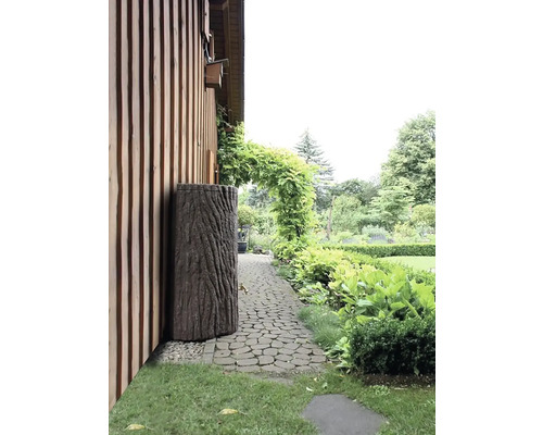 Garten mit Regentonne in Baumstammoptik neben einem Haus