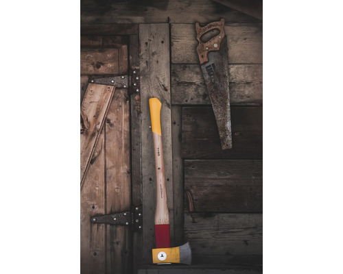 Axt und Handsäge vor Holzwand