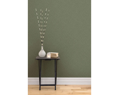 Dekorative Szene mit Tisch, Vase, Kerze und Büchern vor einer strukturierten Tapete