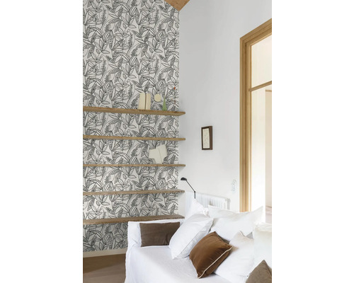 Wohnzimmer mit gemusterter Tapete, Holzregalen und weißem Sofa.