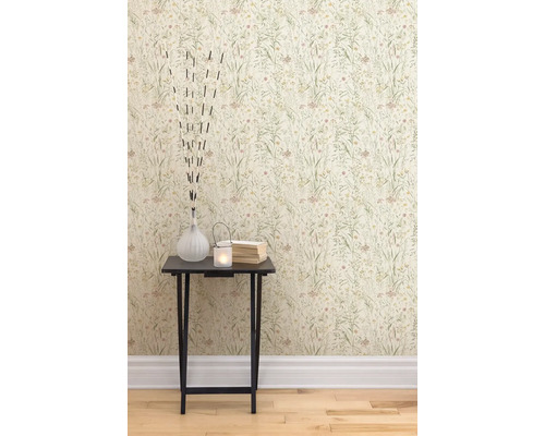 Eine Nahaufnahme einer Wand mit Blumentapete und einem Beistelltisch mit dekorativen Gegenständen wie einer Vase, einem Teelicht und Büchern.