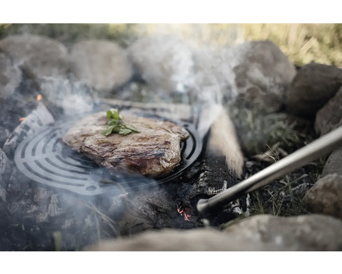 Steak auf Grillrost über offenem Feuerstelle mit Steinen.