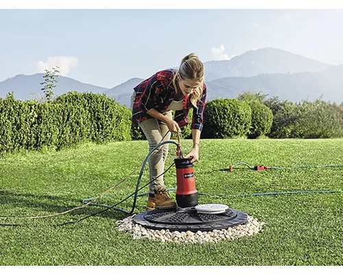 Frau schliesst Tauchpumpe im Garten an