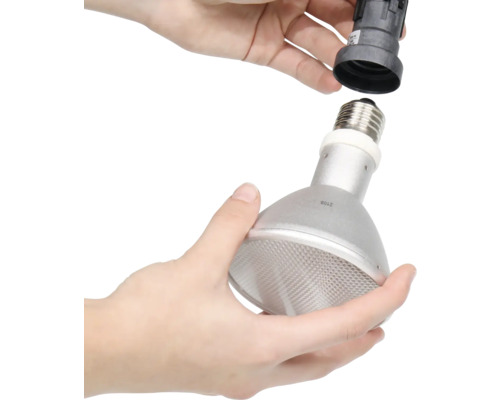 Person schraubt Reflektorlampe in Lampenfassung