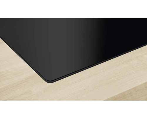 Nahaufnahme eines schwarzen Glaskeramikkochfelds auf einer hellen Holzoberfläche