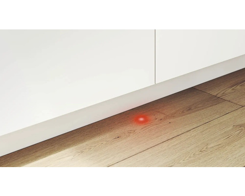Detailansicht eines Möbelstücks mit einem darunter liegenden roten Lichtpunkt auf einem Holzboden