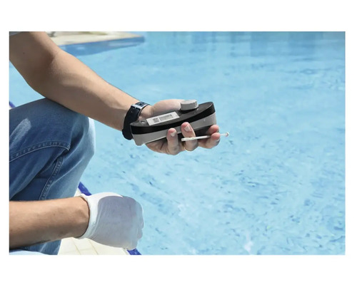 Eine Person misst die Wasserqualität eines Pools mit einem Pooltester.