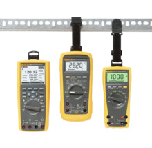 Drei gelbe Multimeter der Marke Fluke hängen an einer Metallschiene.