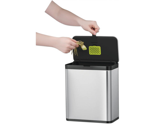 Eine Person wirft Küchenabfälle in einen silberfarbenen Komposteimer.