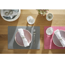Tischdekoration mit Platzsets, Tellern, Besteck, Gläsern, Servietten und Blumenschmuck auf einem Holztisch