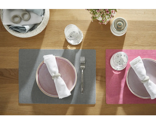 Tischdekoration mit Platzsets, Tellern, Servietten, Serviettenringen, Gläsern, Besteck und Blumenschmuck auf einem Holztisch