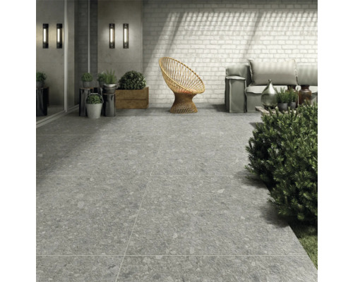 Außenbereich mit grauen Bodenfliesen, Rattan-Sessel und Sitzgelegenheiten