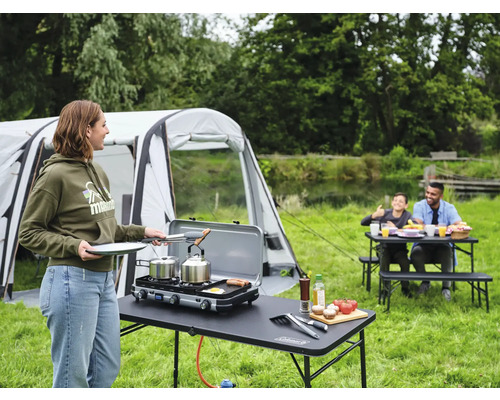 Camping Szene mit Zelt, Tisch, Gasgrill und Familie beim Essen im Freien