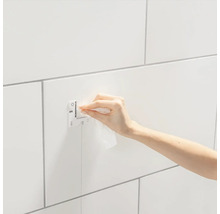 Montagevorrichtung an einer gefliesten Wand mit einer Hand, die sie reinigt