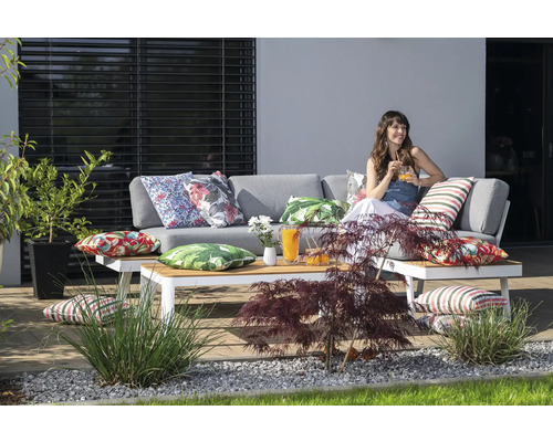 Terrassenszene mit grauer Loungegarnitur, Couchtisch und dekorativen Kissen auf einer Terrasse
