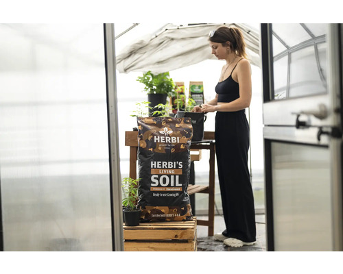 Herbi''s Living Soil Erdmischung im Sack, zusammen mit einer Frau in einem Gewächshaus