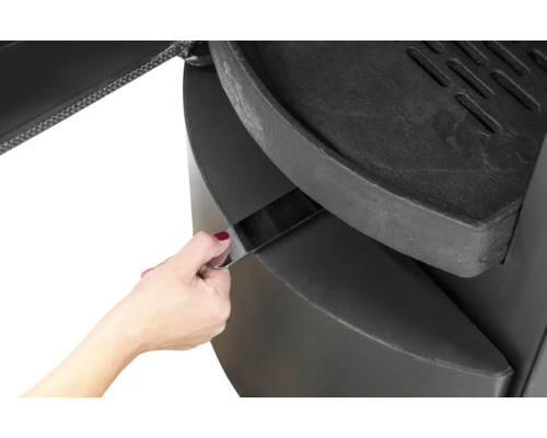 Detailansicht eines Holzofens mit Aschenlade in Bedienung