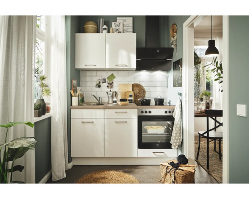 Helle Küche mit Küchenschränken, Spüle, Herd, Ofen, Dunstabzugshaube und Accessoires.