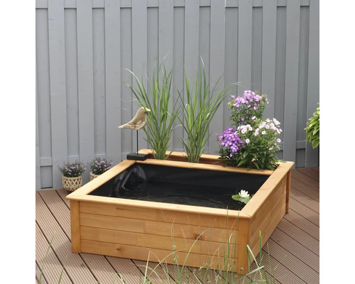 Holzteich mit Pflanzen und Dekoration im Garten